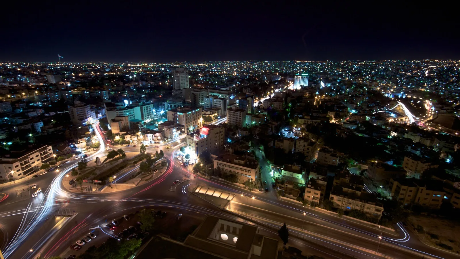 Amman at night, traffic light trails moving through a lit city intersection